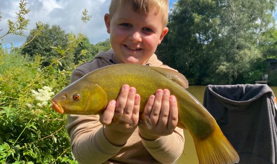 Happy young fisherman and healthy Tench
