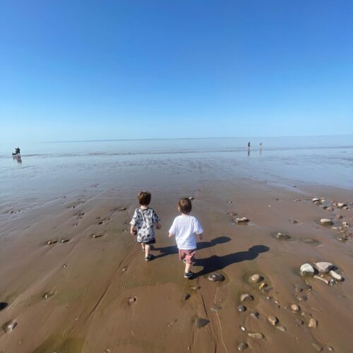 Two boys running to the sea at Blue Anchor beach