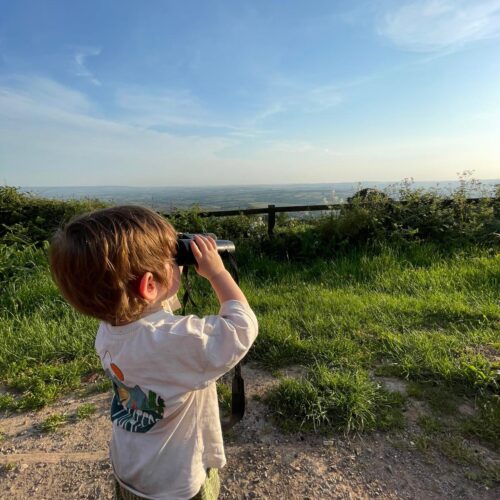 Boy using binoculars to look at the view from Lydeard hill